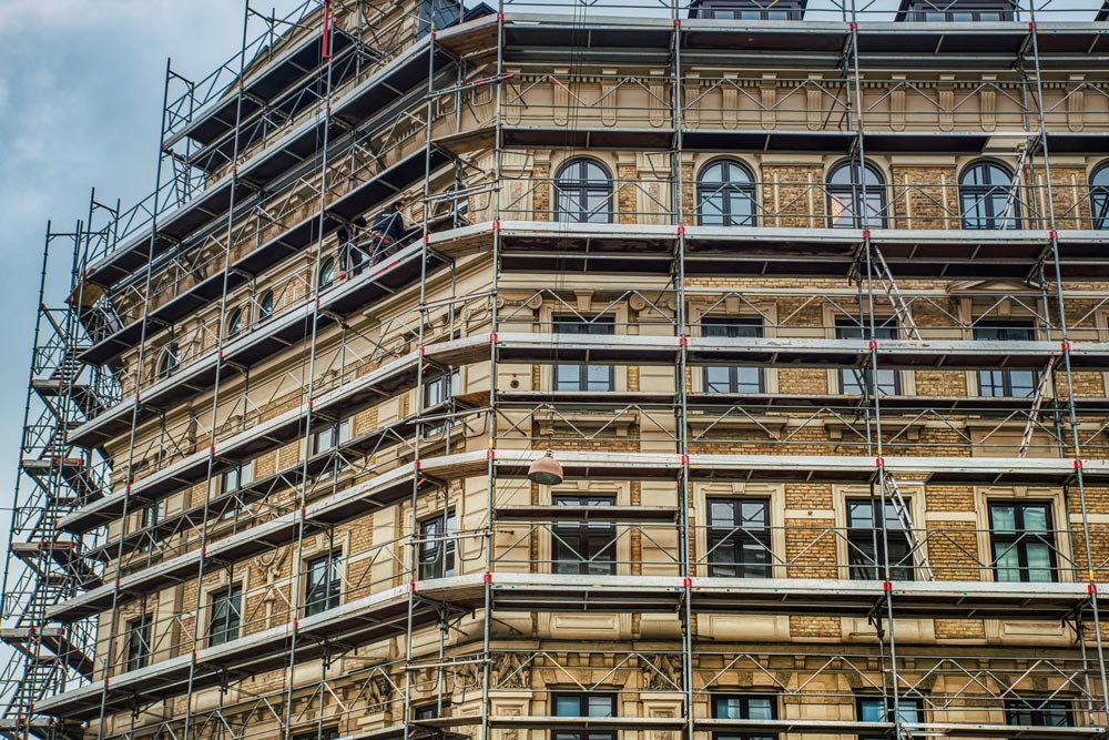 Omfattande byggnadsställningar täcker fasaden av en gul tegelbyggnad av renässansarkitektur