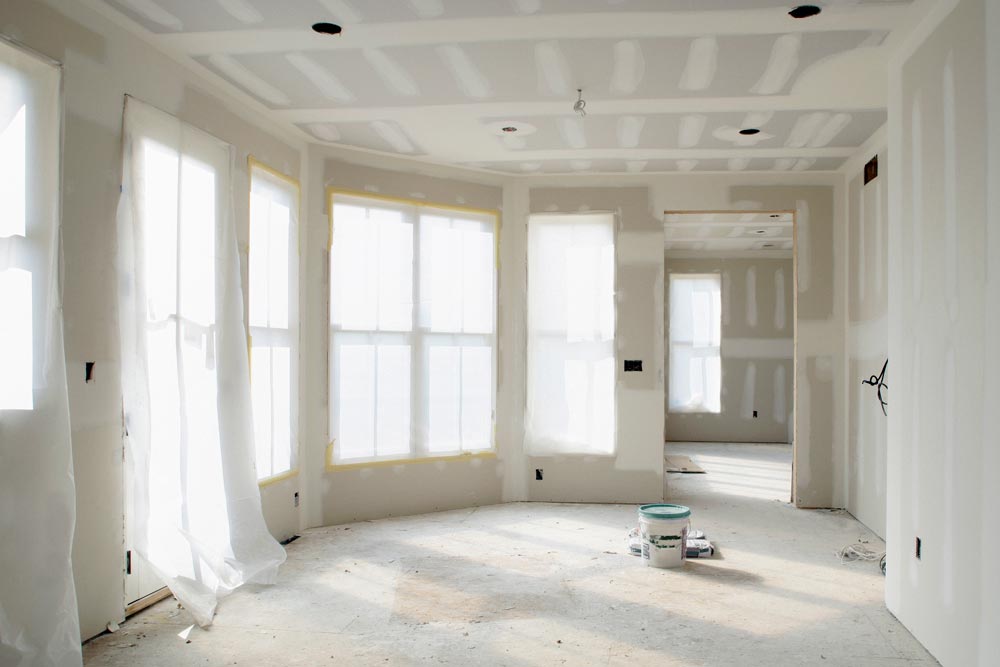 Ett rum under renovering där gipsskiva har applicerats på innerväggar och tak som en del av en hemtillbyggnad